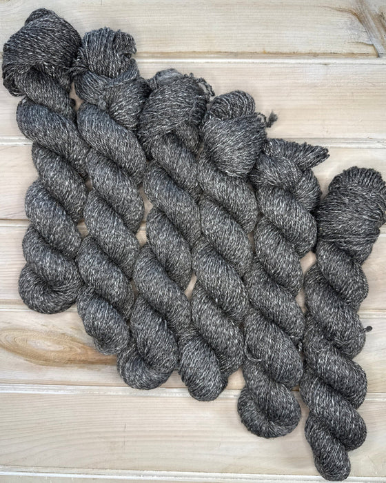 Gray skeins of yarn on a wooden surface