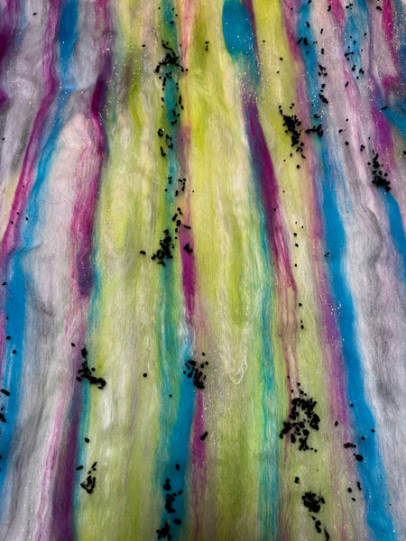 Colorful art batt with black specks on a textured background